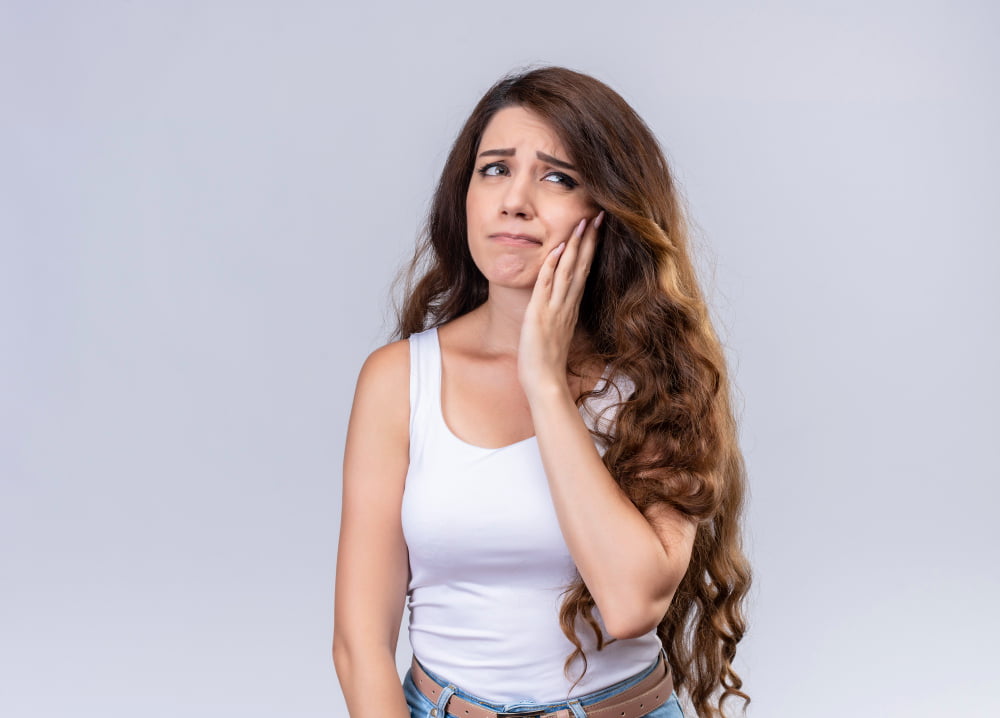 Quanto custa a cirurgia de sisos? 3 aching young beautiful girl putting hand cheek suffering from toothache with copy space