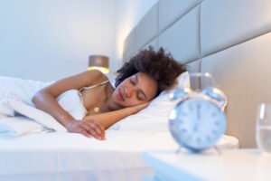 3 escolhas que melhoram suas noites de sono 9 acorde de uma garota adormecida parando o despertador na cama de manha mulher dormindo e acorde para desligar o despertador de manha